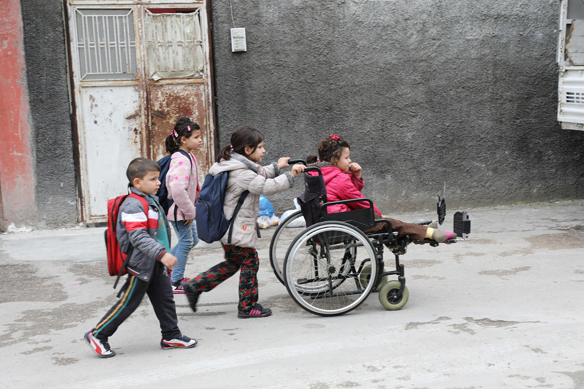 Injured in a bomb blast, Syrian refugee Emine, age 9, is helped by her siblings as they travel to school in Adana, Turkey (UNICEF/Can Remzi Ergen).