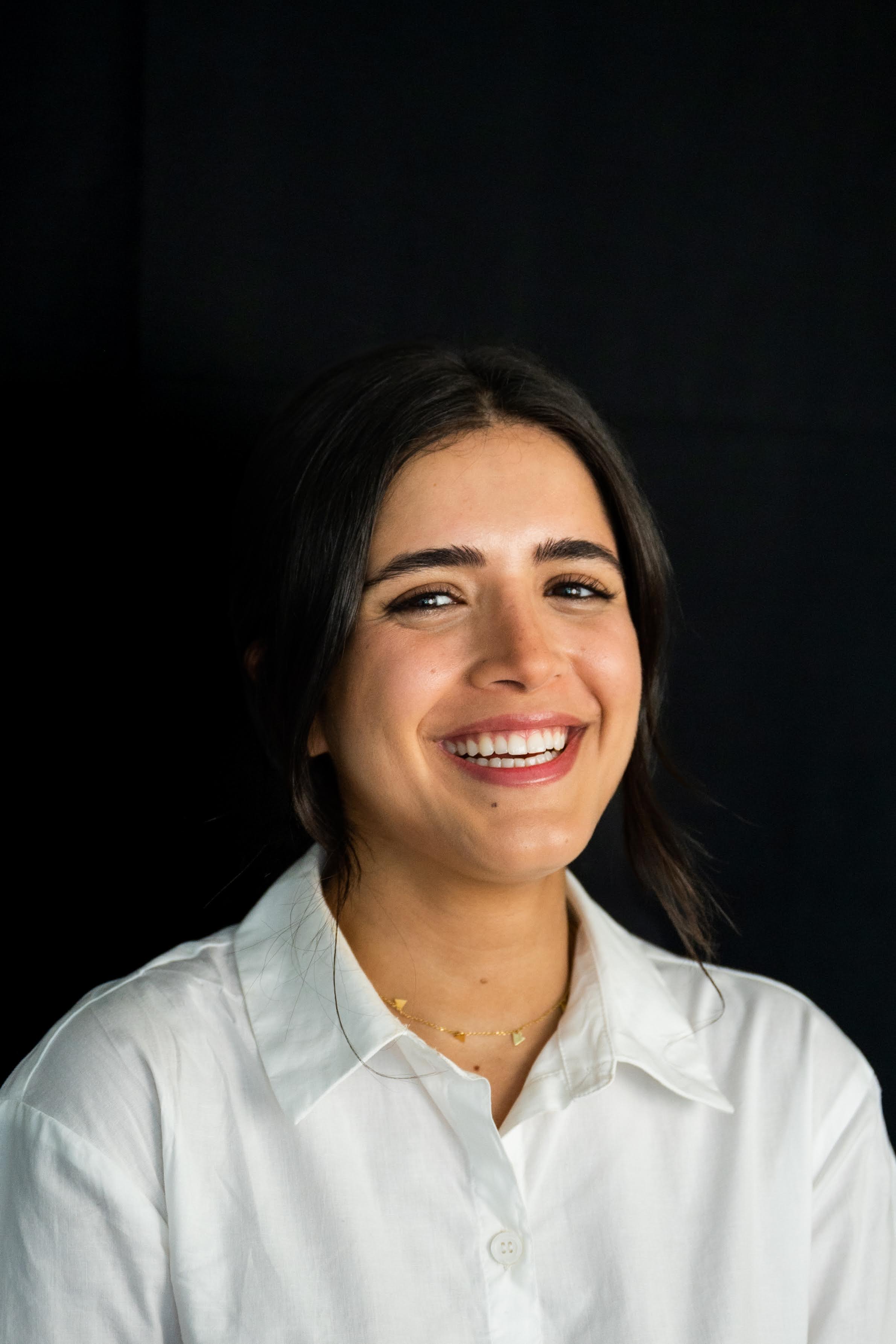 Samar smiling in front of a black background.